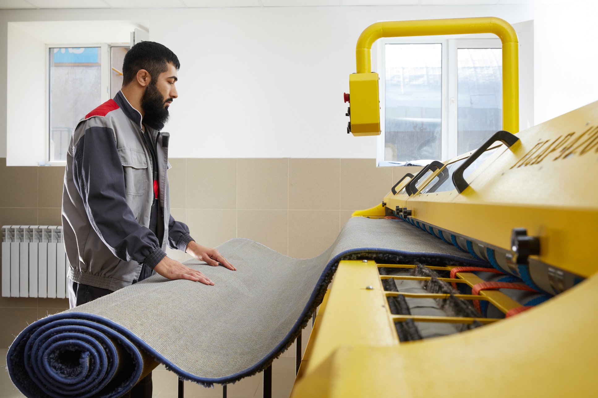 Man Operating Carpet Automatic Washing Machine in Professional Laundry Service